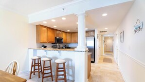A modern kitchen with wooden cabinets, a granite countertop, and a central island with stools.