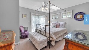 Una camera da letto con un letto a baldacchino, una toeletta con specchio, una sedia e un tavolino.