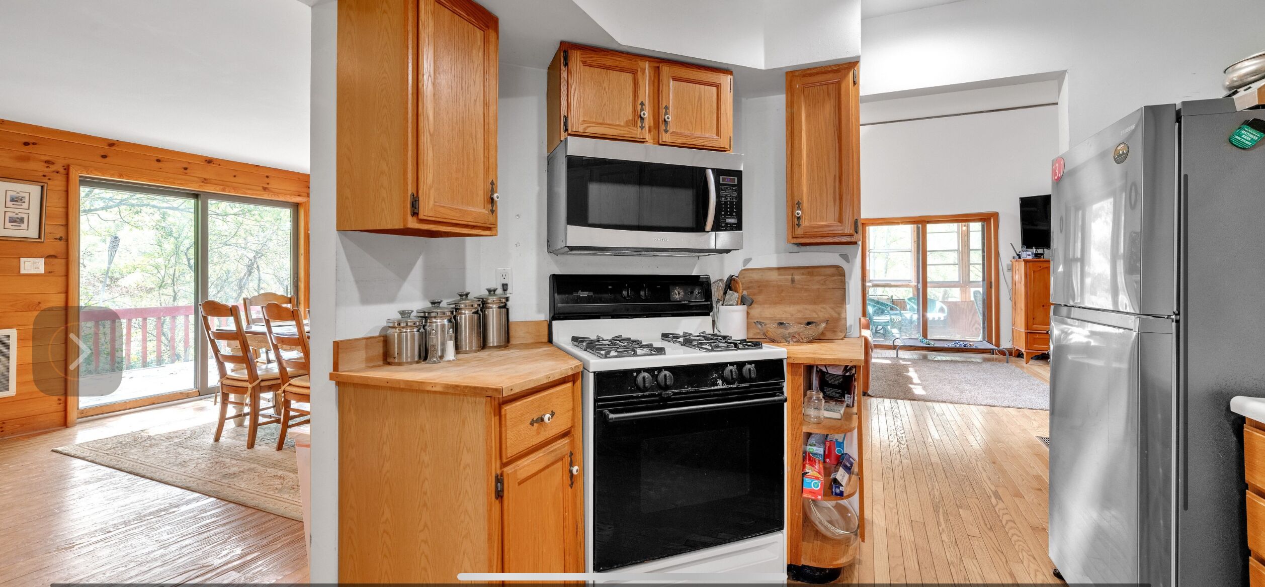 A modern kitchen with wooden cabinets, a gas stove, a microwave, and a refrigerator.