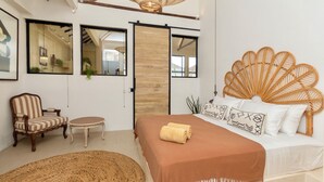 Ein Schlafzimmer mit einem Bett, einem Sessel, einem kleinen Tisch und einem großen Teppich.