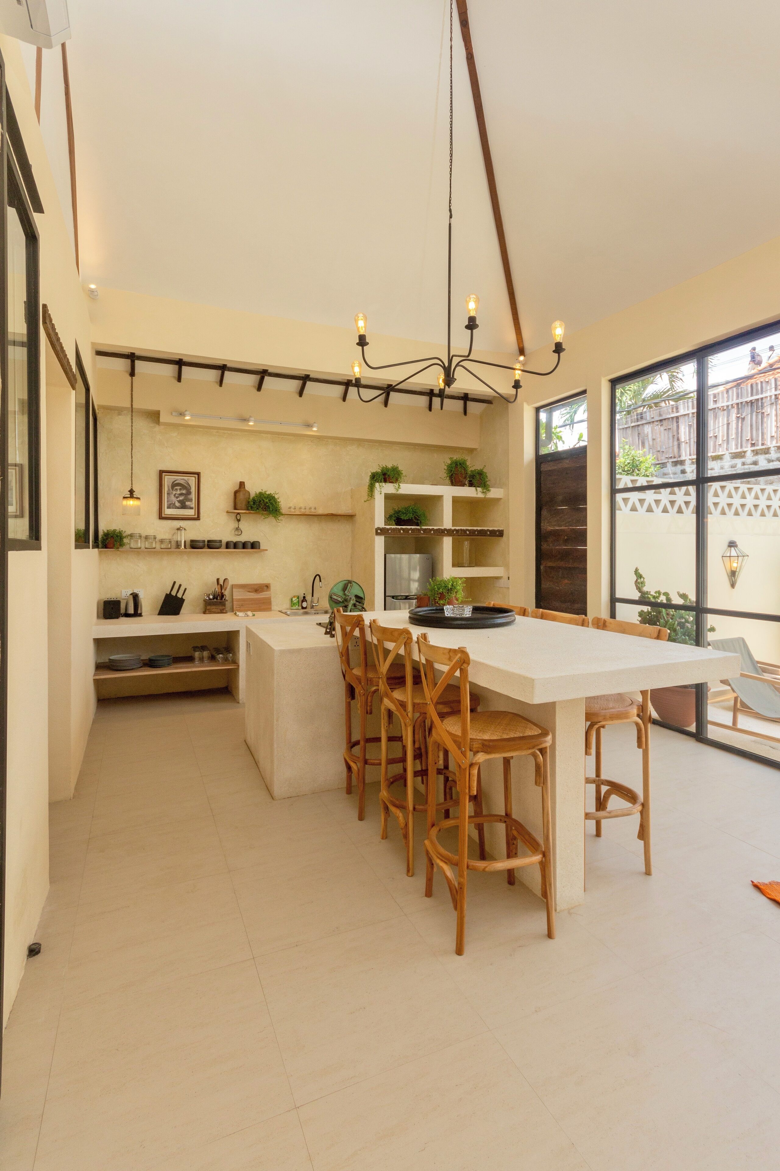 Une cuisine moderne avec un îlot central, des chaises en bois et un luminaire suspendu.
