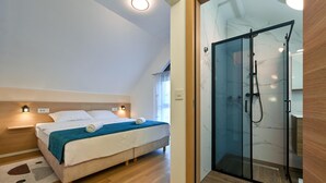 Une chambre moderne avec un lit, des lampes de chevet et une douche fermée par des parois de verre.