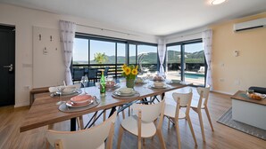 Un coin repas avec une table dressée pour quatre personnes, de grandes fenêtres offrant une vue sur les montagnes et un aménagement intérieur moderne.
