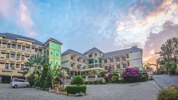 Ein mehrgeschossiges Hotel mit einem zentralen Innenhof, umgeben von üppiger Bepflanzung und Zierpflanzen.