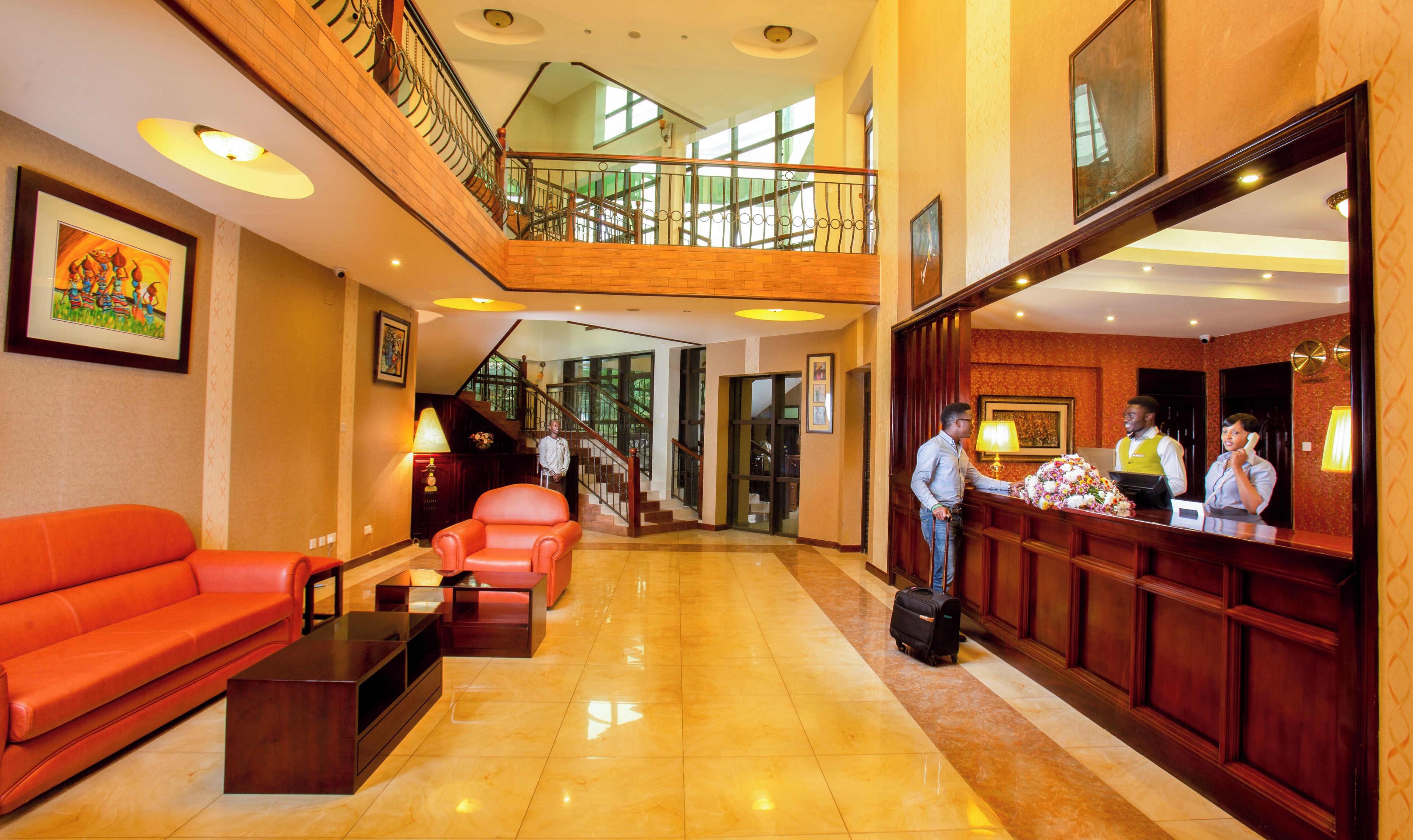 A hotel lobby with a reception desk, a staircase, and a seating area with a sofa and a coffee table.