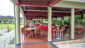 An outdoor dining area with tables and chairs, a covered roof, and a TV screen. - Nyaika Hotel Limited (Fort Portal)