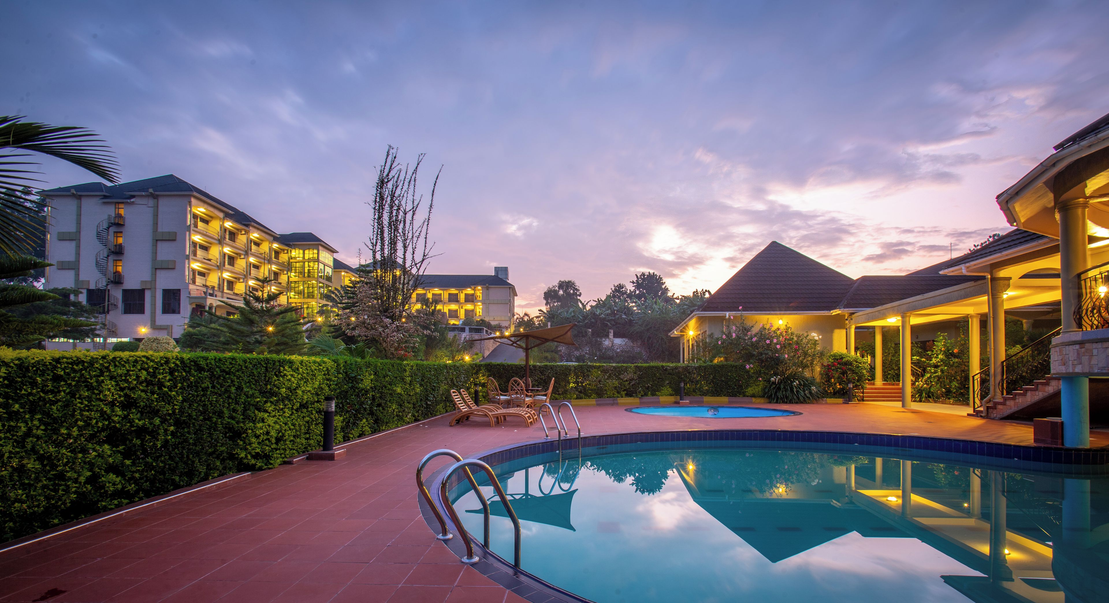 A swimming pool with lounge chairs and a sun terrace, surrounded by well-maintained hedges and a landscaped garden.