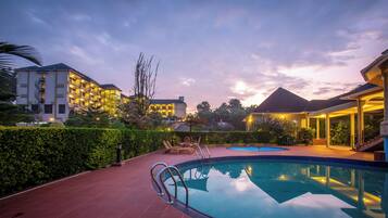 A swimming pool with lounge chairs and a sun terrace, surrounded by well-maintained hedges and a landscaped garden.