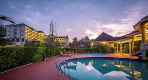 A swimming pool with lounge chairs and a sun terrace, surrounded by well-maintained hedges and a landscaped garden. - Nyaika Hotel Limited (Fort Portal)