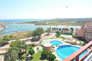 Um resort com várias piscinas, um porto de iates e vista para o mar.