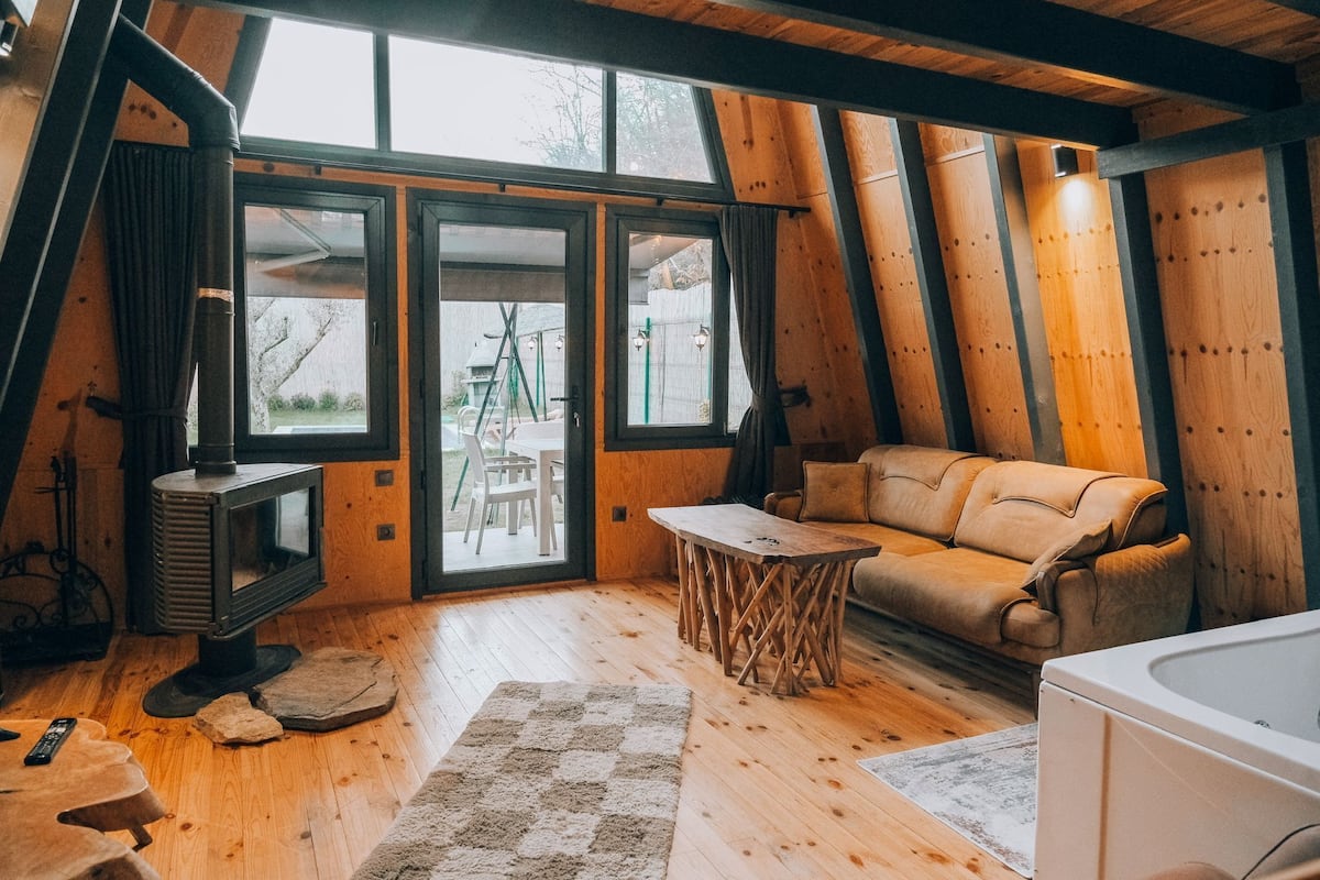 A cozy room with a wooden floor, a sofa, a table, and a fireplace.
