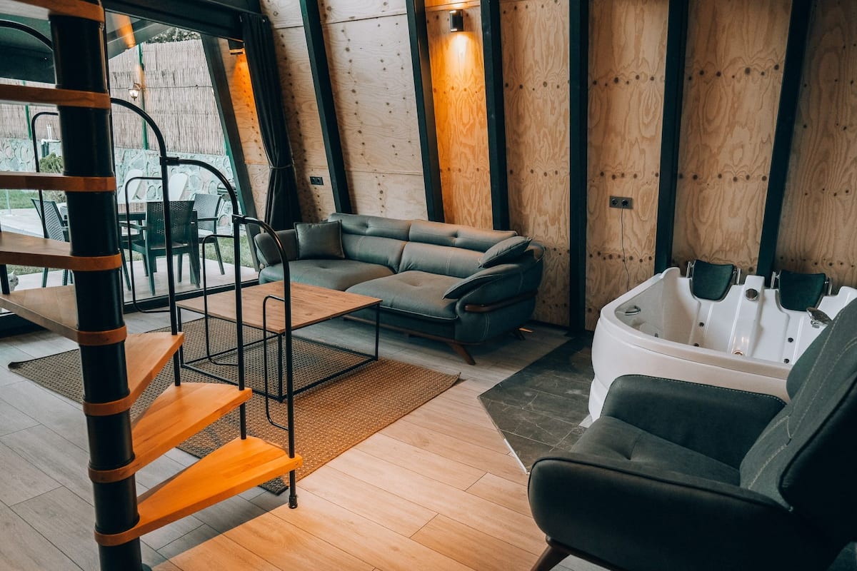 A modern interior with a sofa, a bathtub, and a wooden staircase.