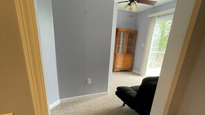 A room with a ceiling fan, a wooden cabinet, and a black chair. - Lakefront two bedroom cottage with Wifi  and Ac on enchanting Idlewild Lake (Idlewild)