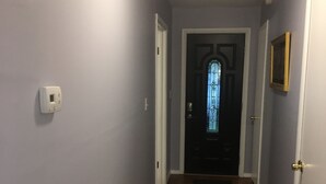 A hallway with wooden flooring, a door with a glass window, and a wall-mounted thermostat. - Lakefront two bedroom cottage with Wifi  and Ac on enchanting Idlewild Lake (Idlewild)
