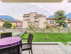 A balcony with a view of a green lawn and buildings in the background.