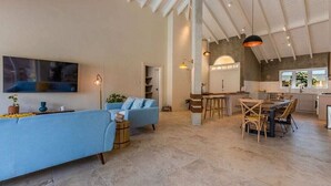 Ein geräumiger Wohnbereich mit einer Couch, einem Esstisch mit Stühlen und einer Küchenzeile mit Bar.