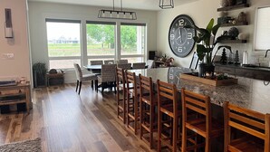 A modern kitchen with a large island, bar stools, and a large wall clock. - Comfortable 3-bedroom house with WiFi in Nampa. (Nampa)