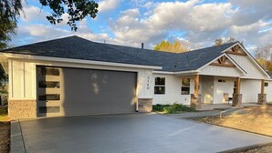 A two-story house with a garage, a driveway, and a well-maintained lawn. - Comfortable 3-bedroom house with WiFi in Nampa. (Nampa)