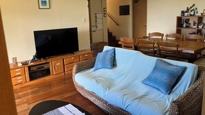A living room with a television, a sofa, a dining table with chairs, and a staircase leading to another room. - South Sea Ishigaki (Ishigaki)
