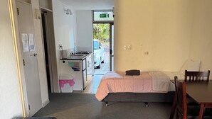 Een kamer met een bed, een bureau, een stoel, een bank en een kitchenette.