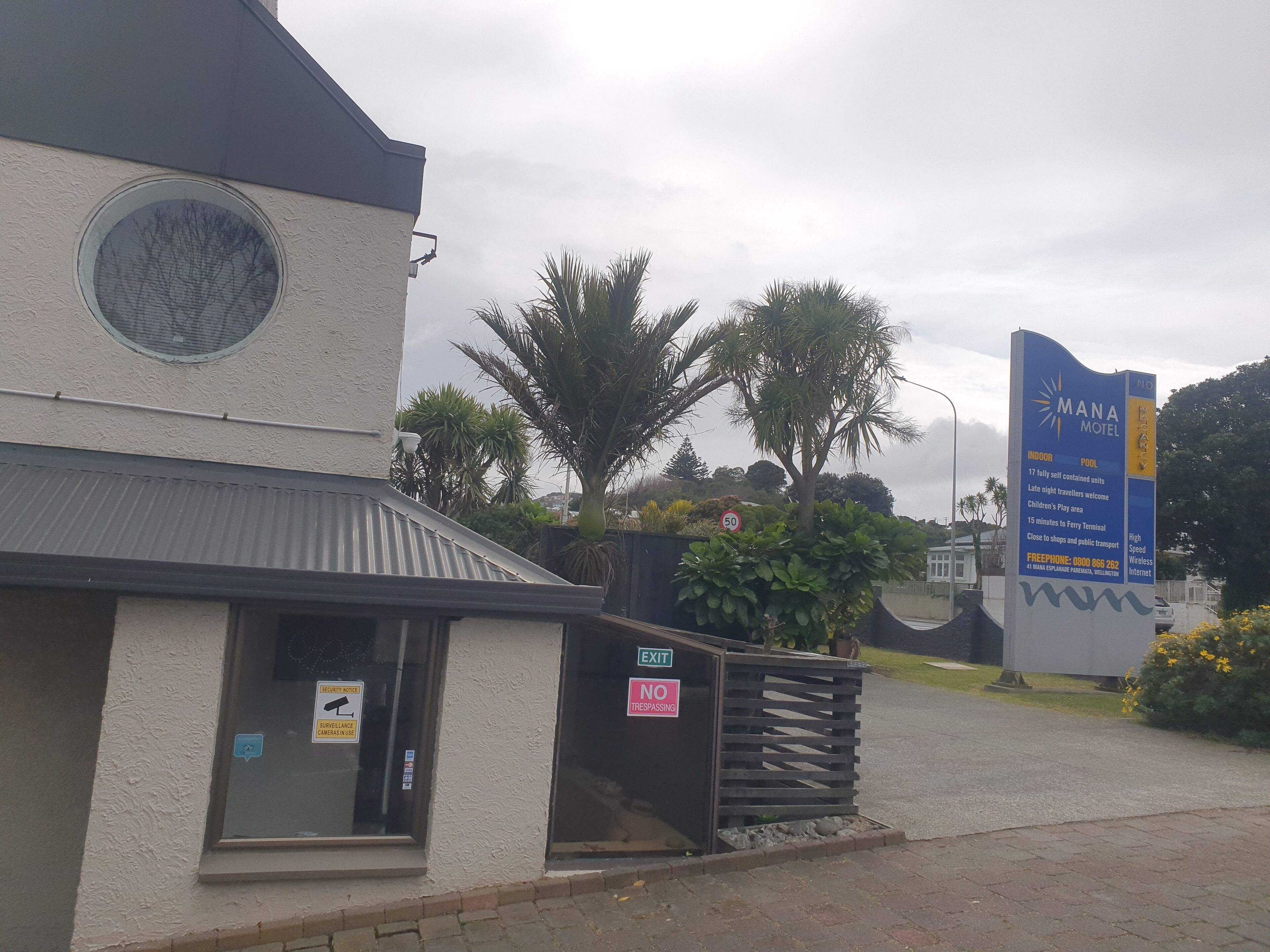 A building with a security camera, a no trespassing sign, and a sign for the Mana Motel.