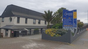 Bordje voor Mana Motel met advertentie voor 17 volledig ingerichte kamers, een zwembad en een kinderspeelplaats.