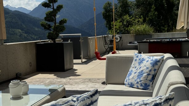 Terraza en la azotea con un sofá, una mesa y vistas a las montañas.