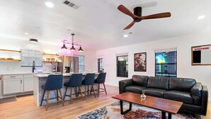 A modern living room with a black leather sofa, a coffee table, and a patterned rug. - Hollywood Vibe Cottage | Game Rm | Near Rainy St. (Austin)