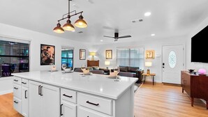 A modern kitchen with white cabinetry, a large island, and pendant lighting. - Hollywood Vibe Cottage | Game Rm | Near Rainy St. (Austin)