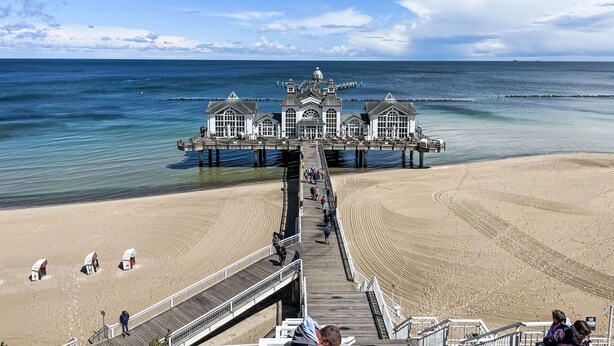 Une jetée qui s’avance dans la mer, avec un bâtiment à son extrémité.