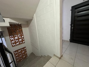Stairway leading to a landing with a black door and decorative panels.