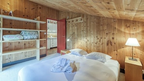 A wooden-paneled room with a bed, a nightstand, a desk, and a wardrobe. - Apt Le Grenier Ski-in/Ski-out views, sleeps 7, Le Tour (Argentière), France (Le Tour (Argentière))