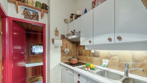 A compact kitchen with white cabinets, a red door, and a tiled backsplash. - Apt Le Grenier Ski-in/Ski-out views, sleeps 7, Le Tour (Argentière), France (Le Tour (Argentière))