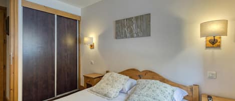 A hotel room with a bed, a nightstand, a lamp, and a painting on the wall.