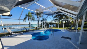 Un espace extérieur abrité avec une piscine, des chaises longues et une vue sur l’eau.