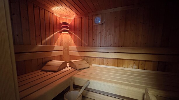 A sauna with wooden benches and a wooden bucket.
