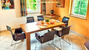 A dining area with a wooden table, six chairs, and a small potted plant.