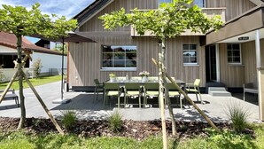 A modern two-story house with a patio area featuring a table and chairs, surrounded by greenery and a clear sky. - Melvill by Interhome (Dittishausen)