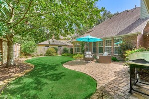 A backyard with a patio area, a covered seating area, and a lawn. - New! 4BR/Easy Access to all Woodlands amenities (Spring)