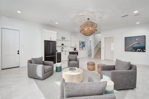 A modern living room with grey sofas, a round coffee table, and a staircase leading to another level.