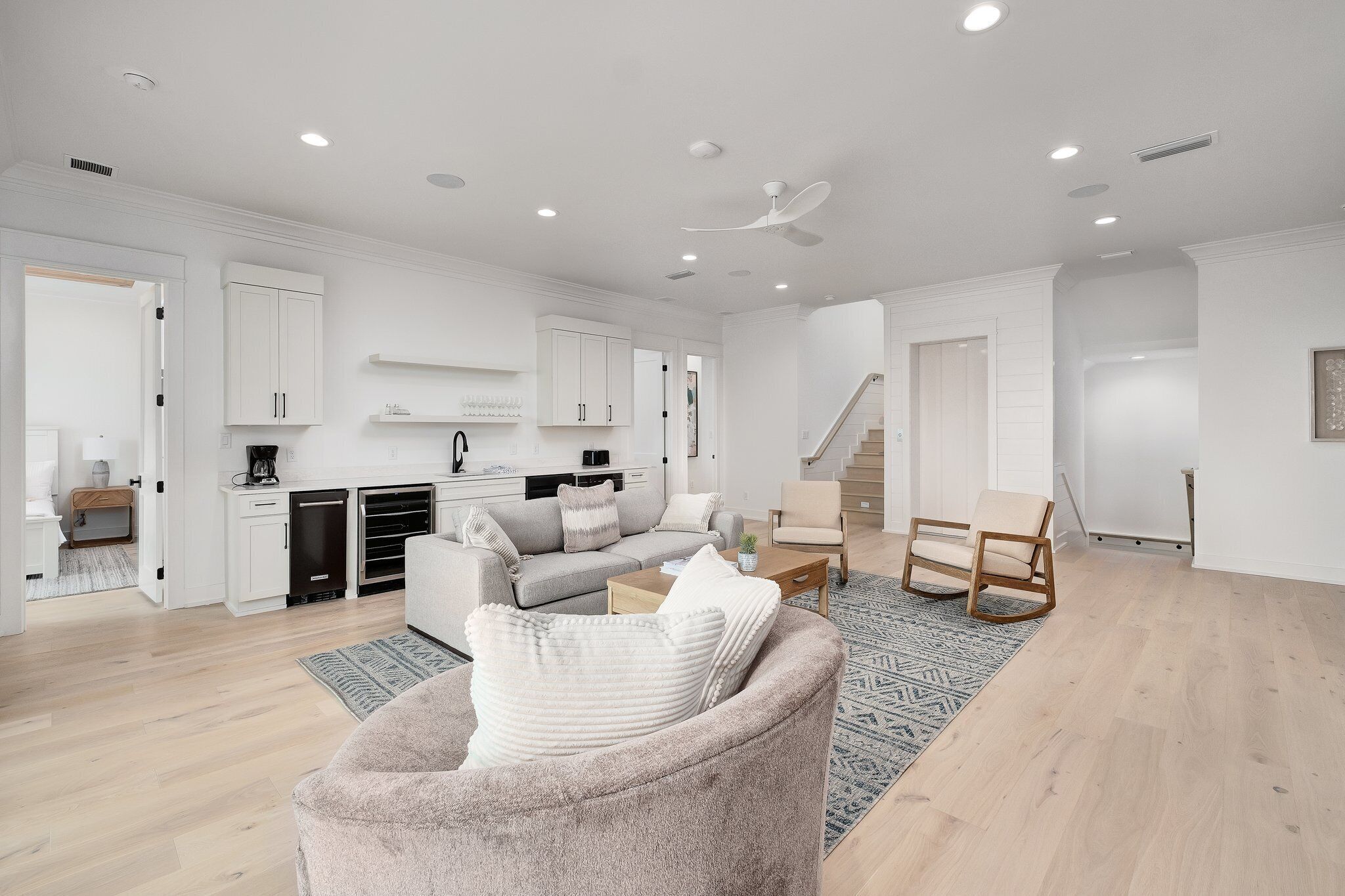 A modern, open-plan living space with a kitchen, dining area, and staircase.