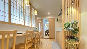 A modern kitchen with wooden cabinets, a dining area with wooden chairs, and a large window with a view. - G1A#[NEW] Tokyo/Shinjuku-ku/New comfortable guest room/5 min. to Shinjuku on JR line (新宿区)