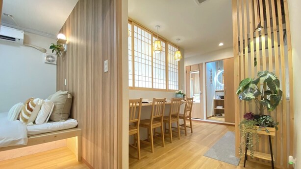 A modern interior with a wooden dining area, a sofa with cushions, and a plant on a stand. - G1A#[NEW] Tokyo/Shinjuku-ku/New comfortable guest room/5 min. to Shinjuku on JR line (新宿区)
