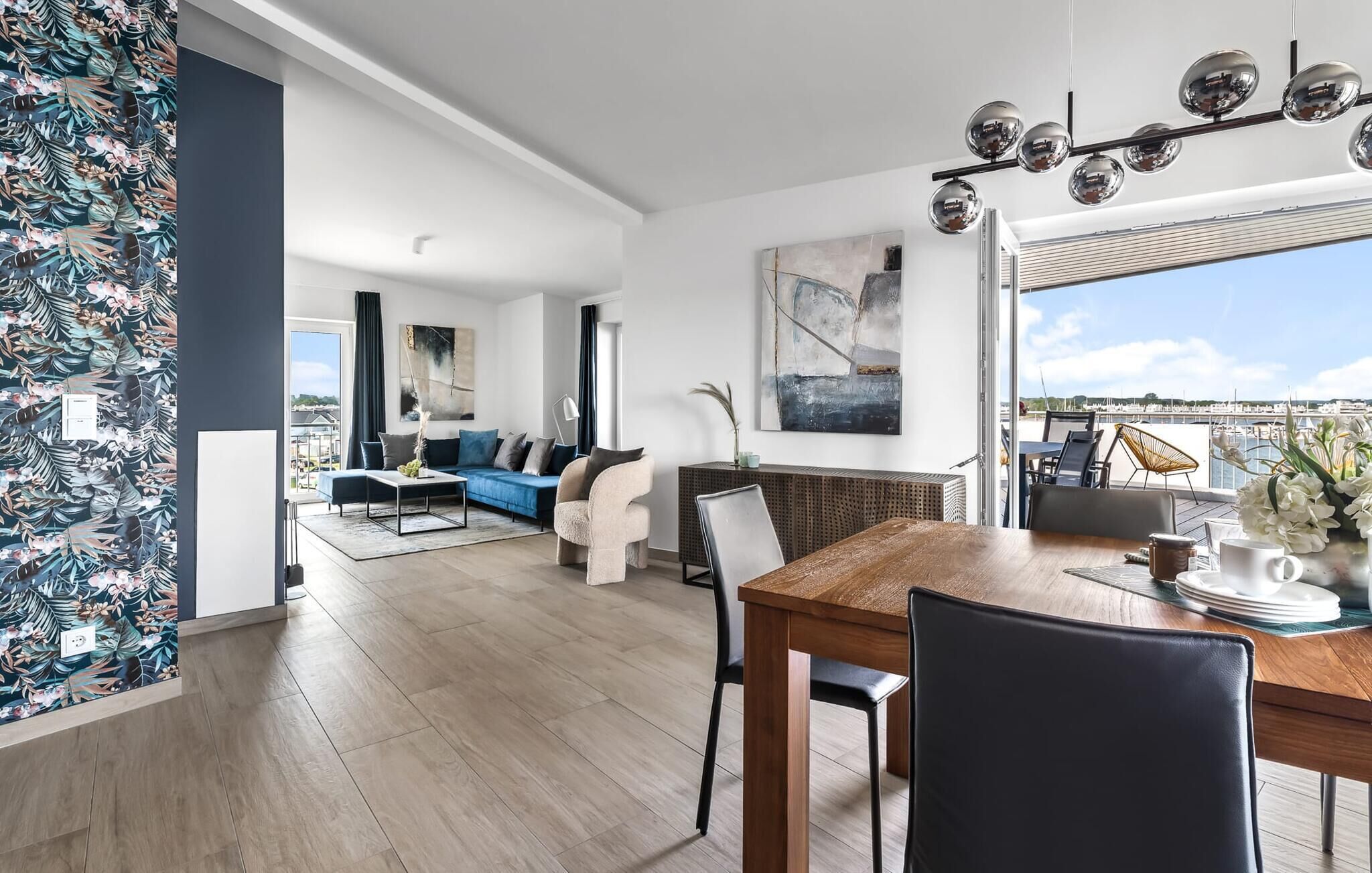 A spacious living area with a dining table, seating, and a view of the marina.