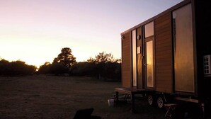 A small wooden cabin with a sliding door, a small porch, and a trailer attached. - Orana Cabin by Tiny Away (Cherry Tree Pool)