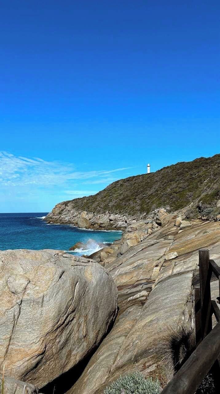 Una costa rocosa con un faro a lo lejos.