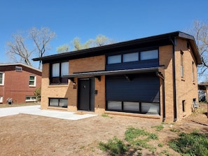 Una casa moderna de dos pisos con garaje, fachada de ladrillo y ventanas amplias.