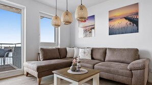 Una sala de estar moderna con un sofá de cuero marrón, una mesa de centro de madera y un ventanal con vistas a un balcón.