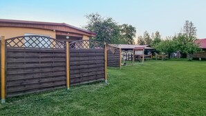 A fenced backyard with a small building and a covered structure.