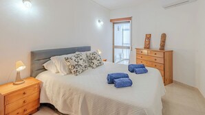 Un dormitorio con cama, mesita de noche, cómoda y ventana.